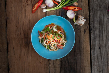 Top view of Thai spicy seafood salad with prawns, squid and Thai mussels isolated on wooden table