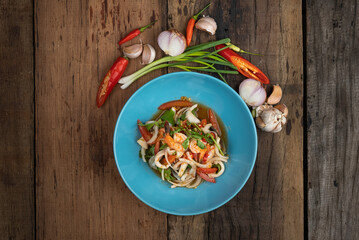 Top view of Thai spicy seafood salad with prawns, squid and Thai mussels isolated on wooden table