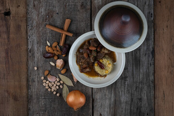 Top view of slow cooked lamb with potato and dates served with warm couscous and chickpeas isolated on the wooden table