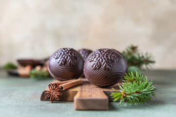 Tasty cocoa bombs with marshmallow and chocolate on wooden plate with fir branches and spices. Trendy winter hot drink. 