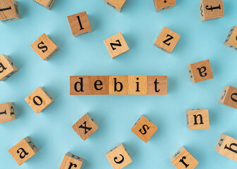 Debit word on wooden block. Flat lay view on blue background.