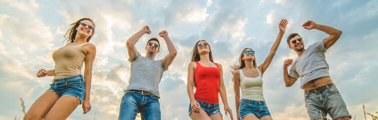 The five friends dancing on the background of the clouds