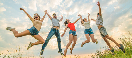 The happy friends jumping on the background of the clouds