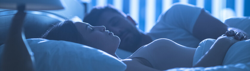 The attractive woman sleeping near a man in the comfortable bed. night time