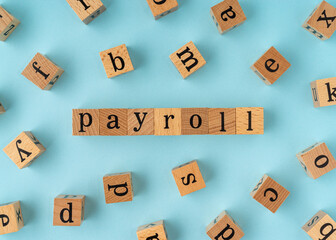 Payroll word on wooden block. Flat lay view on blue background.