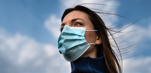 The beautiful woman in medical mask standing outdoor