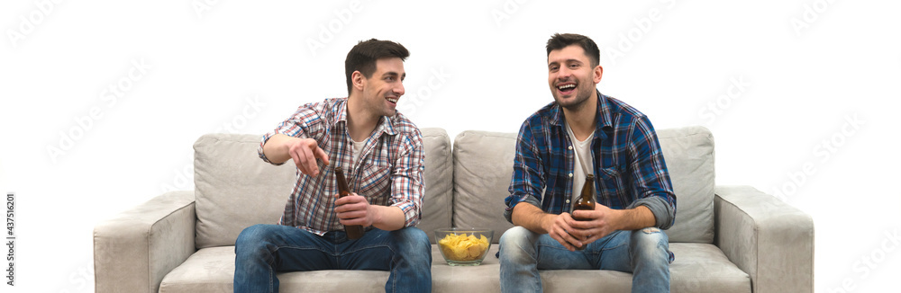 Wall mural The two men drink a beer with chips on the sofa on a white wall background