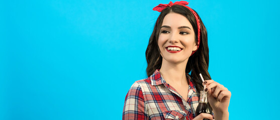 The happy girl standing with a bottle of drink on the blue background
