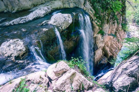 A scenic stream of a waterfall falling among a rocky gorge. Agur river in Khosta microdistrict, Russia. Travelling, hiking and recreation in the mountains.