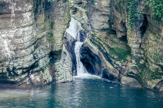 A scenic stream of a waterfall falling among a rocky gorge. Agur river in Khosta microdistrict, Russia. Travelling, hiking and recreation in the mountains.