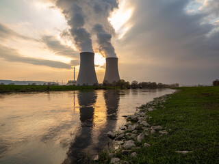 Nuclear power plant against sky by the river at sunset