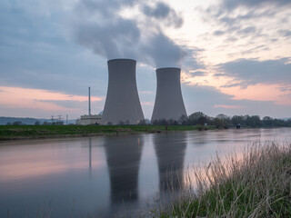 Nuclear power plant against sky by the river at sunset