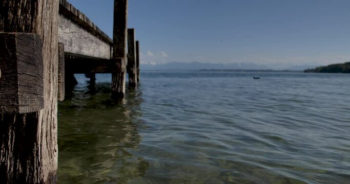 Wooden pier at German lake "Starnberger See" with alps and blue sky