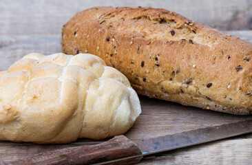 Due pagnotte di pane con coltello, pane naturale su sfondo di legno adatto per contenuti sui...