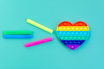 Top view of colorful anti stress sensory toy pop it. rainbow heart on green background close up....