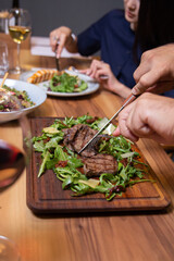 man in the cafe eats beef steak with greens close-up