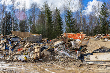 Illegal dump in the woods. Environmental pollution from construction waste. Negative impact on nature. Construction debris has accumulated in the forest.