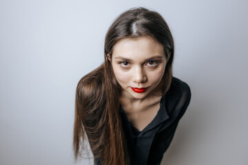 Beautiful girl with red lips looking at the camera. Close-up portrait on a light gray background.