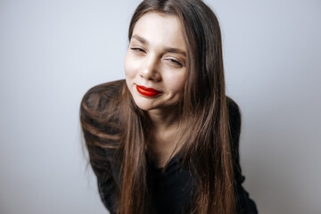 Beautiful girl with red lips looking at the camera. Close-up portrait on a light gray background.