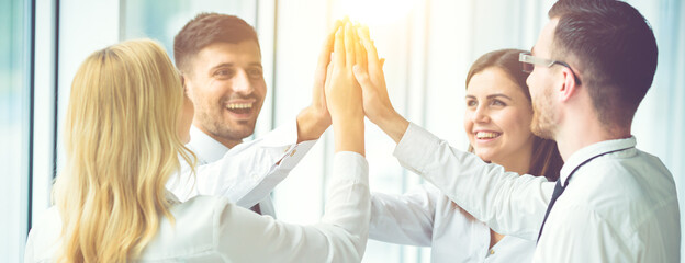 Fototapeta premium The four happy people greeting with a high five on the sun background