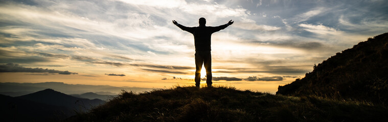The happy man standing on the rock with the picturesque sunrise