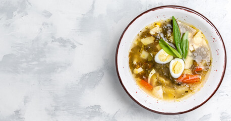 Fresh dietary soup orrel and eggs, potatoes on a white background. called green borsch for weight loss, Long banner format. top view