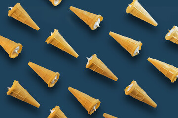 Waffle cones with white sweet filling on a dark blue background. Sweet waffle cones with filling. Image of a sweet treat.