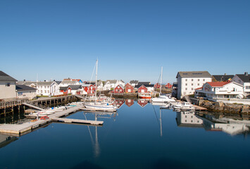 View of the port of Veiholmen, Smøla, Norway. Beautiful summery day with houses and boats reflected in the calm sea.