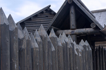 A protective palisade around a wooden log house in a Russian village. Traditional Russian construction of huts.