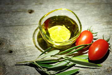 古い木のテーブルを背景に置かれたミニトマトとオリーブオイル