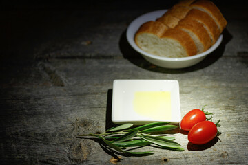 古い木のテーブルを背景に置かれたミニトマトとオリーブオイルとバケット