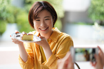 ケーキを持ち写真を撮る女性
