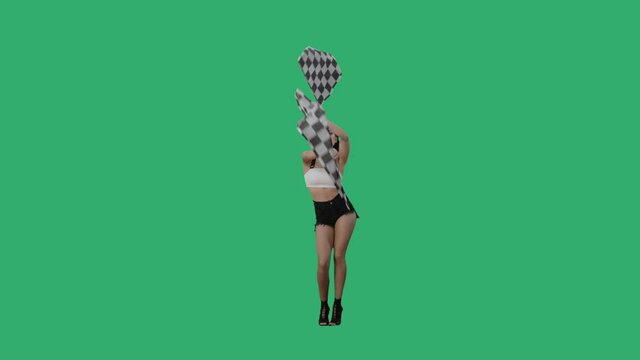 Sexy brunette in short shorts waving black and white checkered racing flags. Young woman posing full length against a background of a green screen in the studio. Slow motion ready, 4K at 59.94fps.