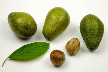 Whole ripe avocado fruits avocado leaf and avocado seeds lie on a white table
