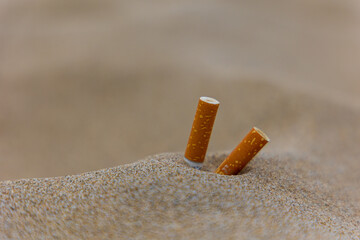 Sandy beach close up of two cigarette butts