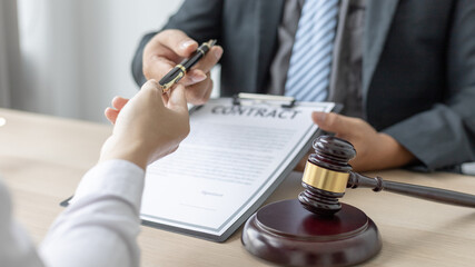 Attorney or lawyer handing client a pen to sign a business contract, Signing the contract according to the terms and conditions, scales of justice, law hammer, Concept of litigation and legal services