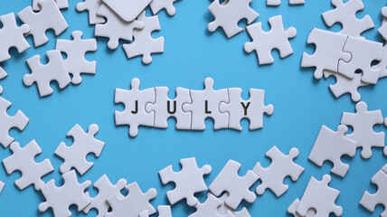 JULY word written on white jigsaw puzzle