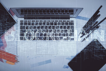 Blockchain theme hologram drawings over computer on the desktop background. Top view. Multi exposure. Concept of cryptoeconomy.