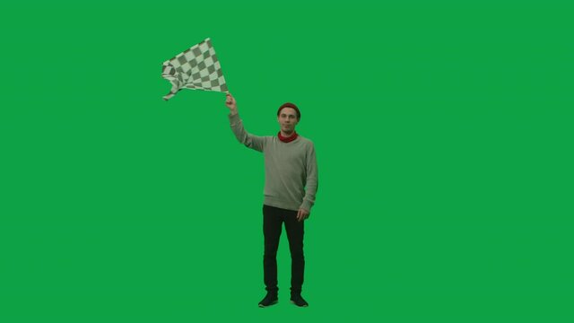 Portrait of a young man in youth stylish clothes and hat waving black and white checkered race flag. Full length on green screen background. Slow motion ready, 4K at 59.94fps.