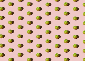 Bright fruit pattern with fresh organic green apples against pastel pink background. Creative summer vibes idea, minimalistic colorful concept.