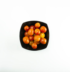 Fresh tomatoes placed on a black plate on a white background