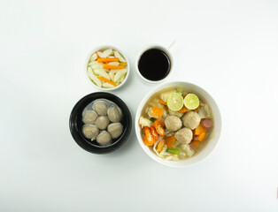 Indonesian Food | Omelet, pickled cucumber meatballs and meatball soup on a wooden cutting board on a white background