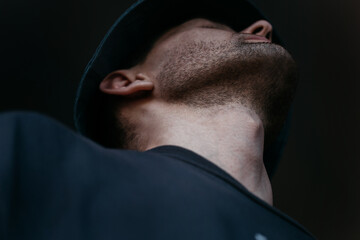 Naklejka premium The neck of a guy in a panama hat and a black T-shirt looks up in close-up.