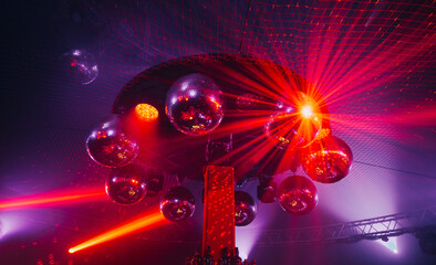 Disco ball suspended to the ceiling in the club during the concert, shining with red colour. mirrors reflect a bright light at discotheque.