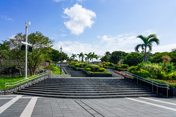 Naklejka premium 沖縄の青い空と青い海、海洋博公園の中央ゲートに至る美しい花壇のある石段