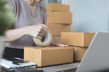 Young asian woman entrepreneur, online store owner packing products parcels, preparing to deliver...