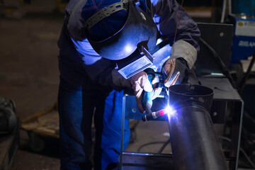 Skillful welders weld steel in the factory. Construction site metal welder.