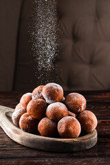 Donuts sprinkled with powdered sugar on wooden table on dark background