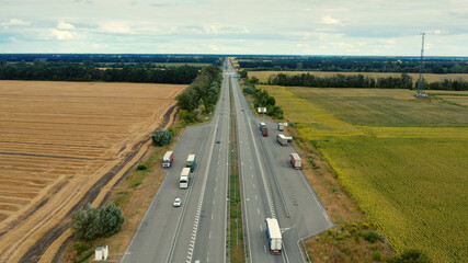 Aerial view of a motorway in summer on a cloudy day. Aerial view of a suburb road with trucks. Drone  above a highway with driving cars.