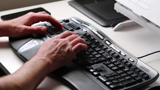 Business man or professional programmer typing on ergonomic keyboard with ergonomic mouse in home office workplace with modern computer equipment from home with European hands of a male person closeup